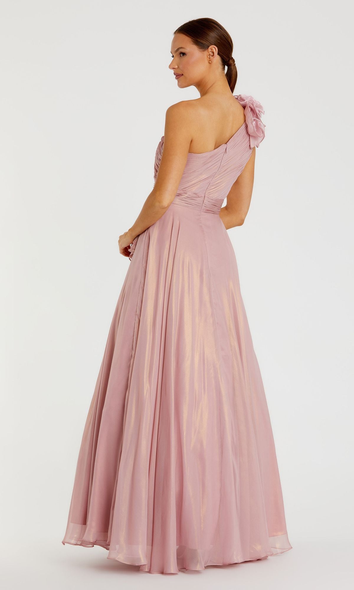A woman wearing the Mac Duggal 49252 long rose gold formal dress, featuring a one-shoulder design with floral detail, stands looking to the side.